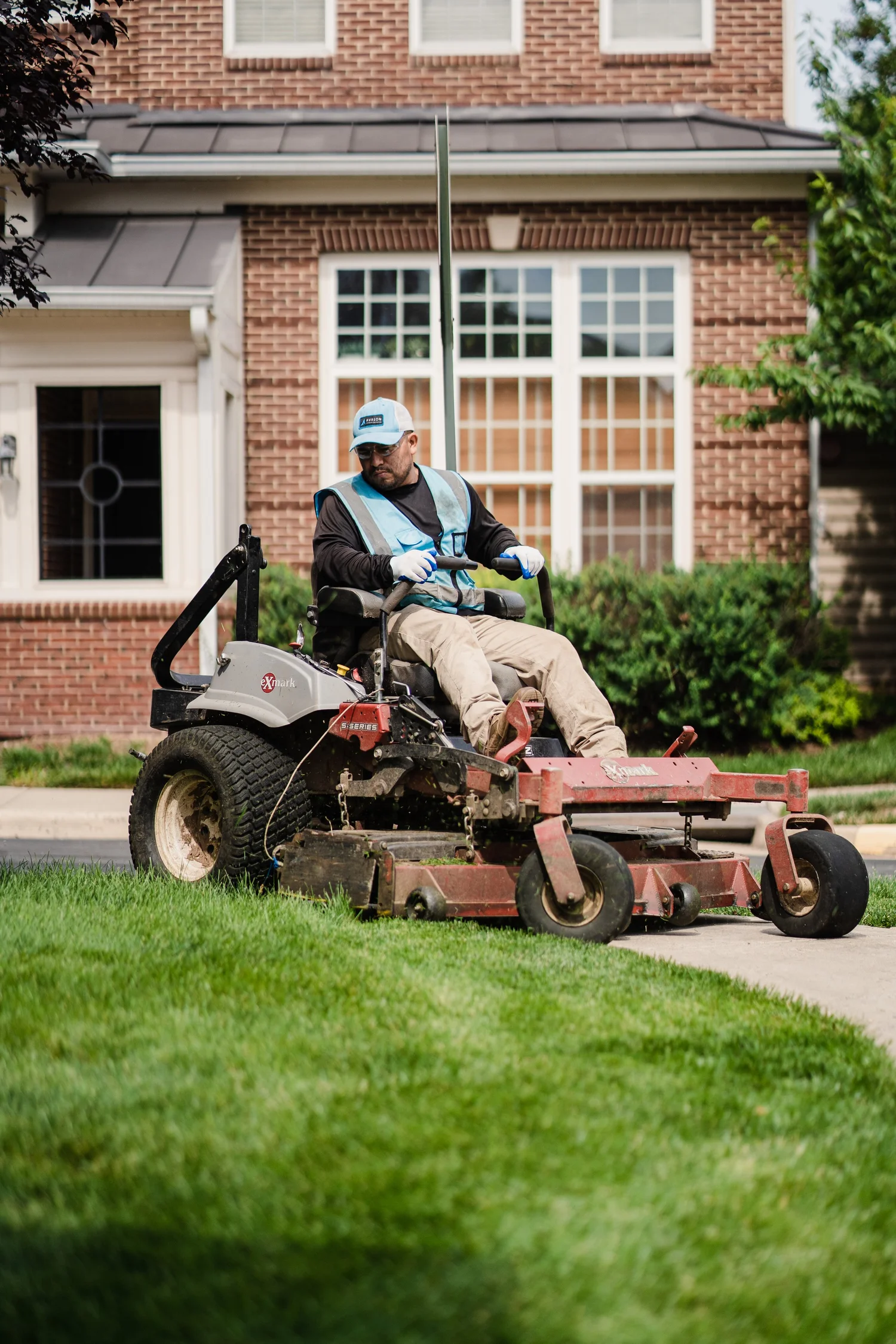 Avalon crew member on a zero-turn mower servicing a multi-family townhome community