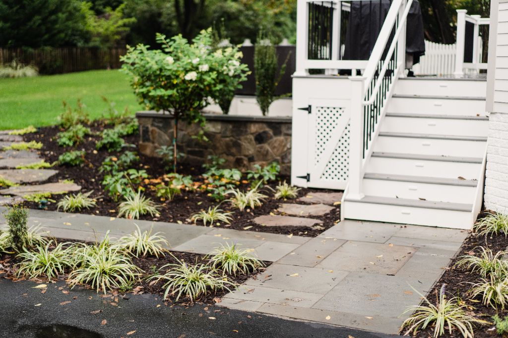 Farmhouse patio with stone wall and hydrangea garden