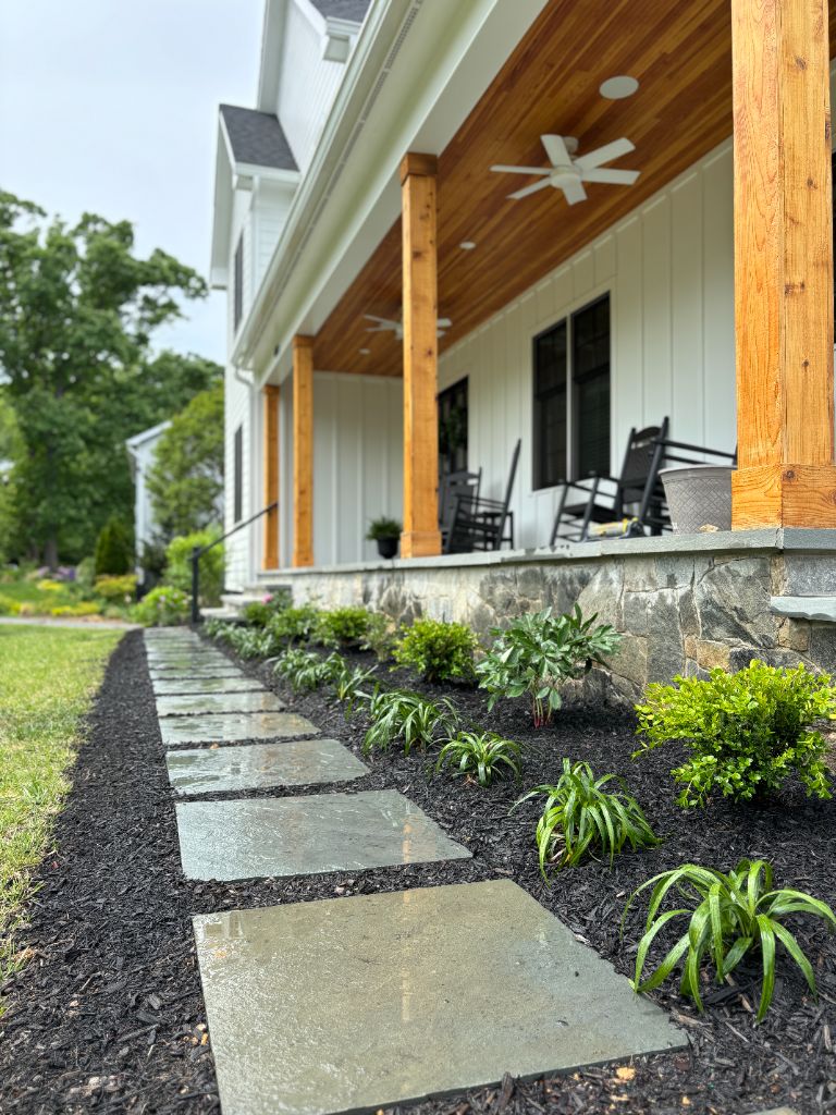 Bluestone stepping stones alongside white farmhouse porch with stone foundation