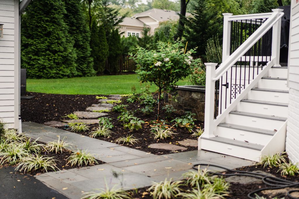 White farmhouse with bluestone walkway and hydrangea garden