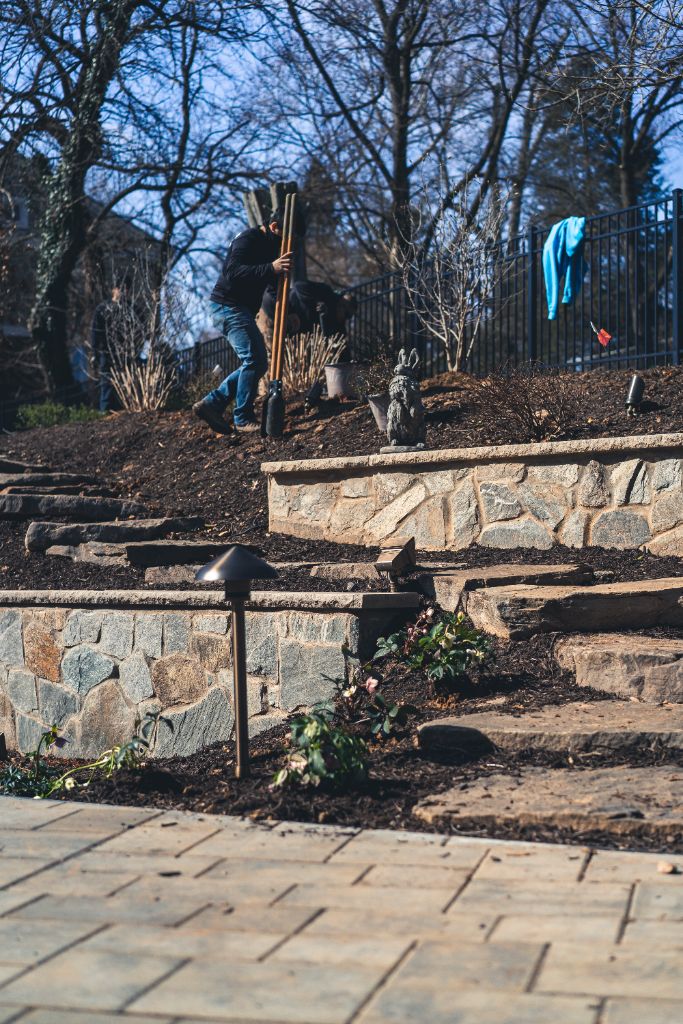 Multi-tier fieldstone retaining walls with paver patio and path lighting