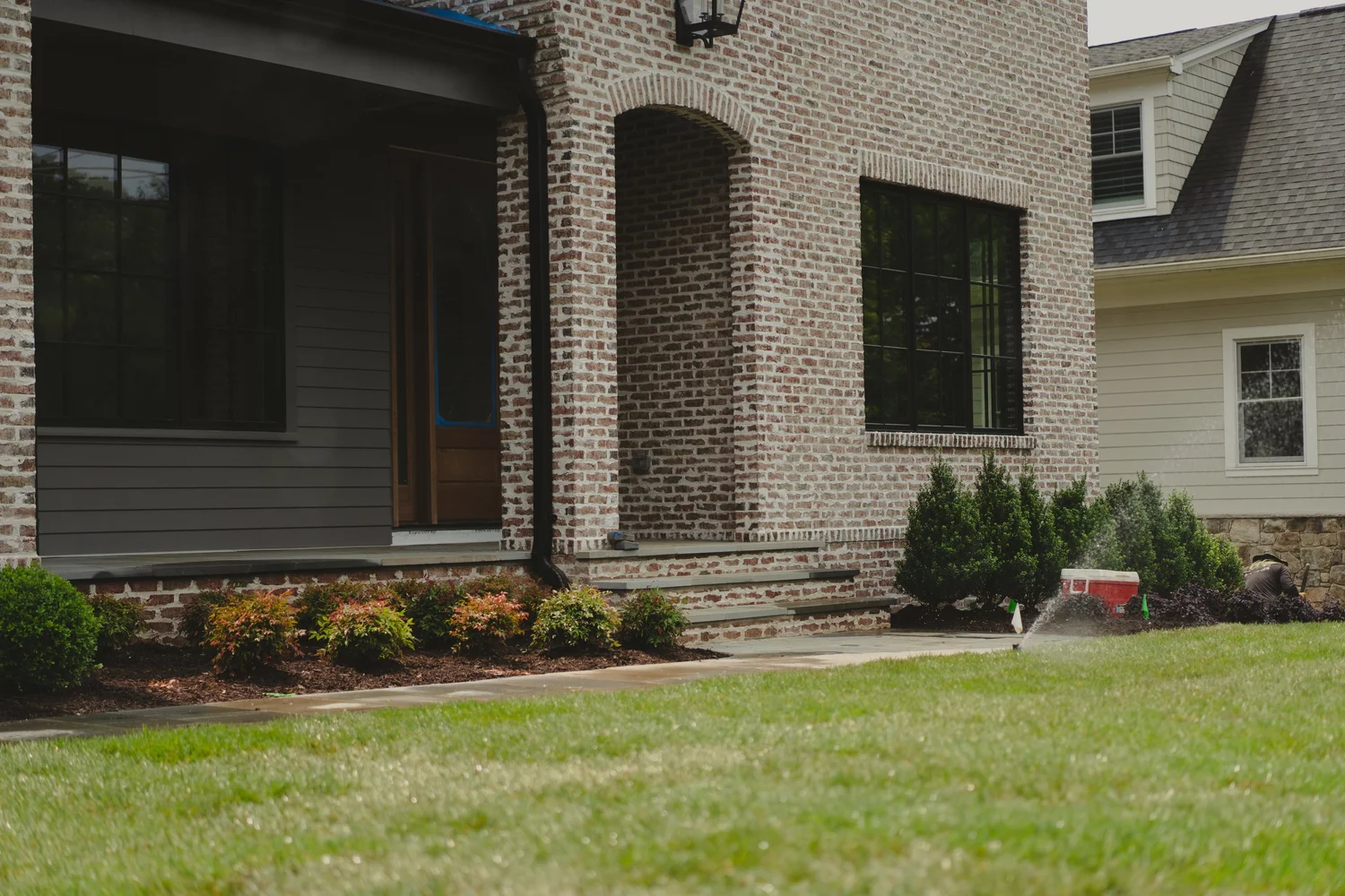 In-ground irrigation head spraying water across a lawn and garden bed