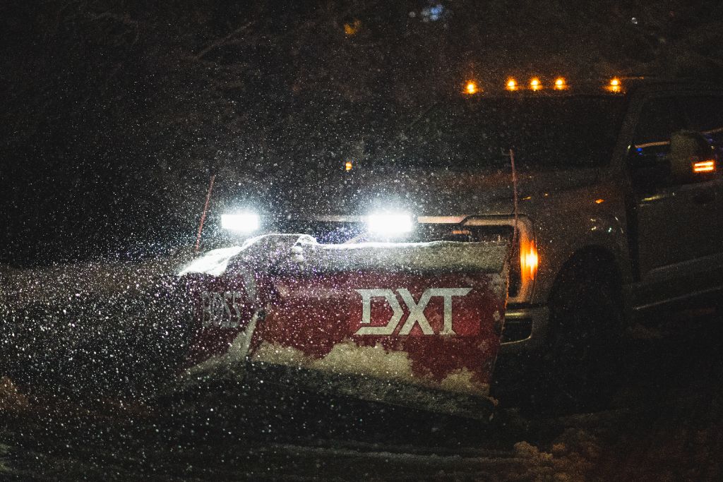 BOSS DXT plow spraying snow at night